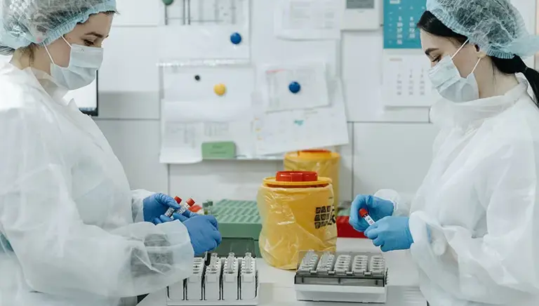 Two scientists working together, holding a set of vials