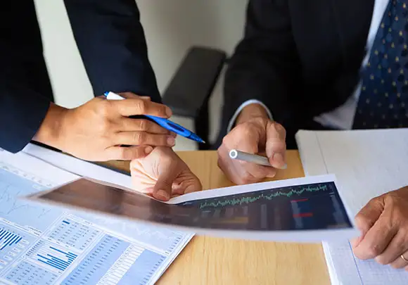 Close up of the hands of two office workers holding print outs of charts